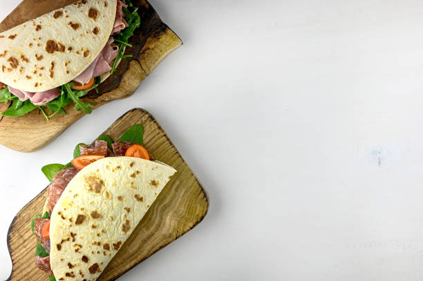 istock tasty wrapped flatbread with vegetables and prosciutto on a wooden table. 1687054013
