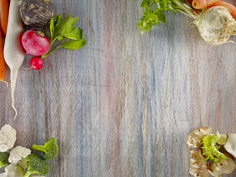 Raw root vegetables on wooden colored background.