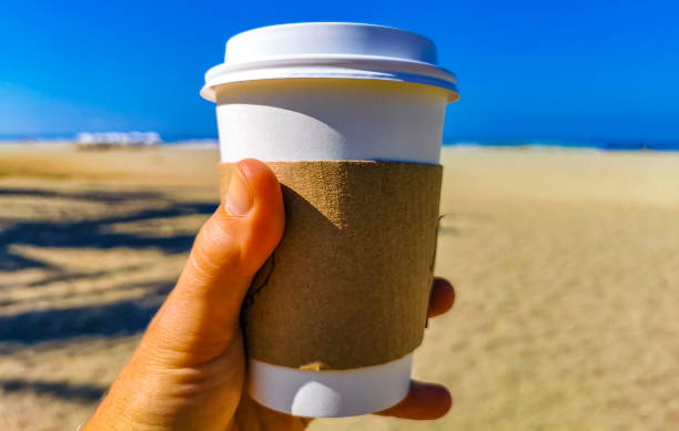 istock Coffee to go mug on the beach sand sea waves. 1687080720
