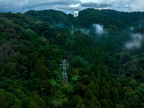 Aerial view of steel towers, power transmission lines, electric lines, and high-voltage lines built deep in the mountains