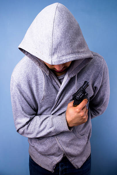 istock Man in grey hood clutching a handgun 168710431