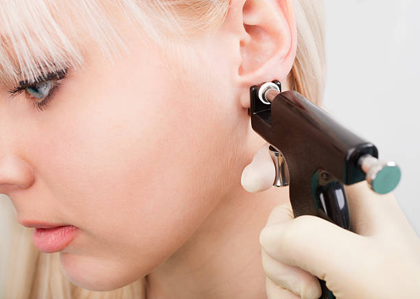 Woman having ears pierced with ear piercing gun Beauty center by medical worker. piercing stock pictures, royalty-free photos & images