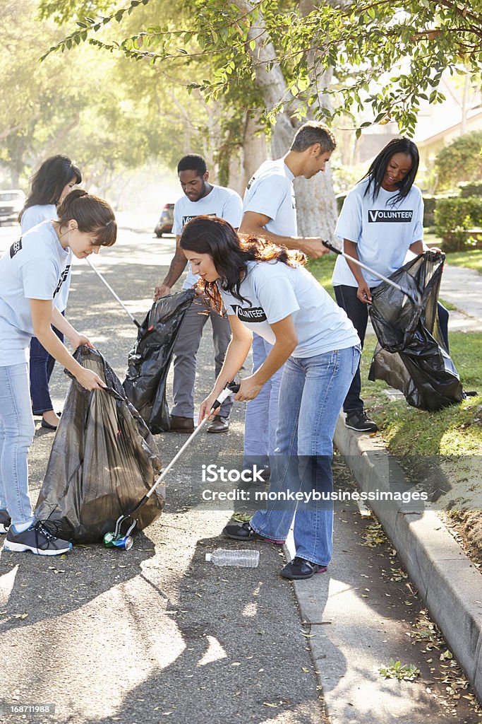 Team Of Volunteers Picking Up Litter In Street Team Of Volunteers Picking Up Litter In Suburban Street Cleaning Stock Photo