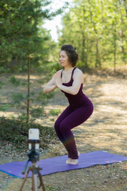 istock Young woman doing yoga in nature online using phone and application 1687122000