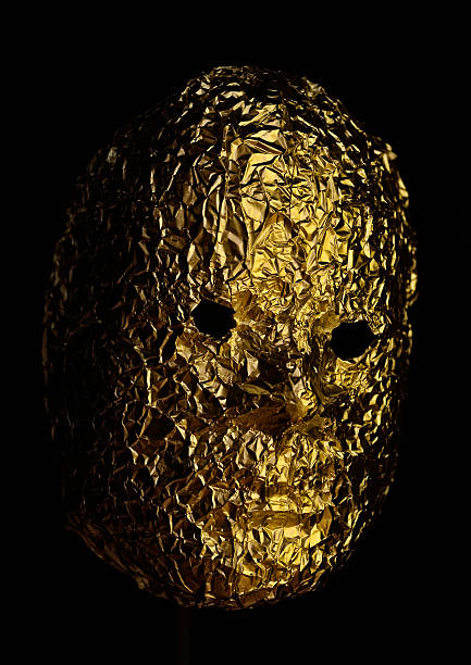 A gold-colored foil mask against a black background.