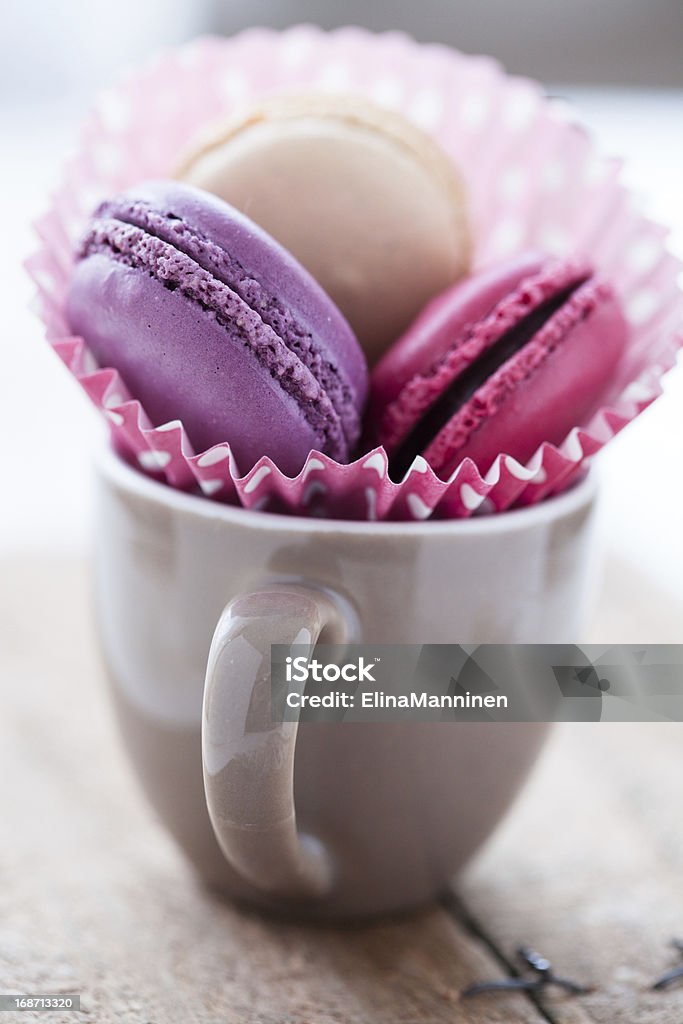 Macaroons in cup Closeup of three different flavoured macaroons in cup on wooden table Baked Pastry Item Stock Photo