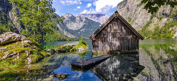 Idyllisches Bild eines Fischerhauses am Obersee mit dem Watzmann-Massiv im Hintergrund im Nationalpark Berchtesgaden