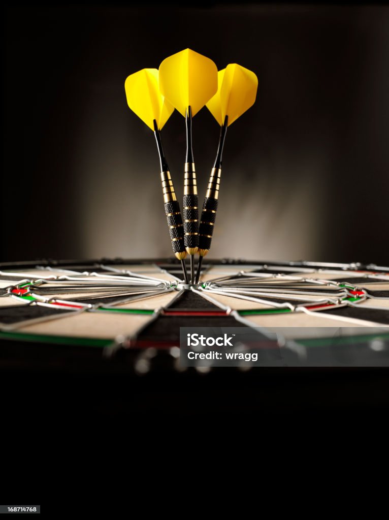Copy Space in Darts Three yellow darts hitting the target in a game of darts scoring a bulls eye. Copy space Darts Stock Photo
