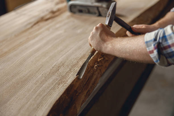 istock Close up of craftsman working with chisel while cutting wooden plank in carpentry workshop 1687153998