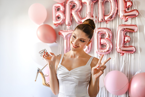Young bride writes the names of her single friends bottom of her bridal shoes