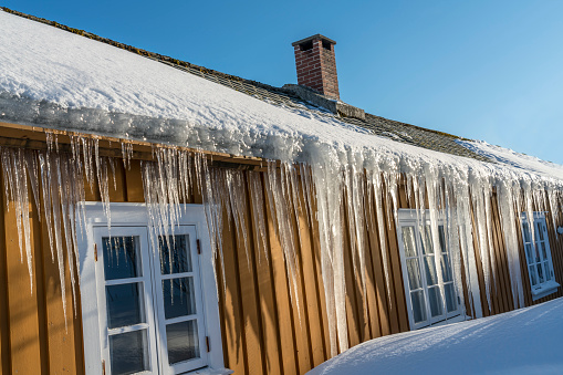 Winter view on wooden cottages in winter with many long icicles hanging from the roof. Village of Sakrisoy on tiny island in the Lofoten archipelago in Norway.