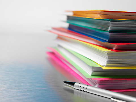 Coloured paper business files on a stainless steel background with copy space.  Differential focus. 