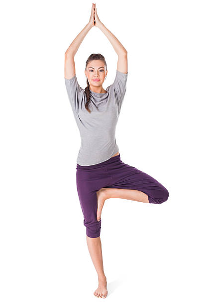 Young woman doing yoga exercise tree-pose isolated on white
