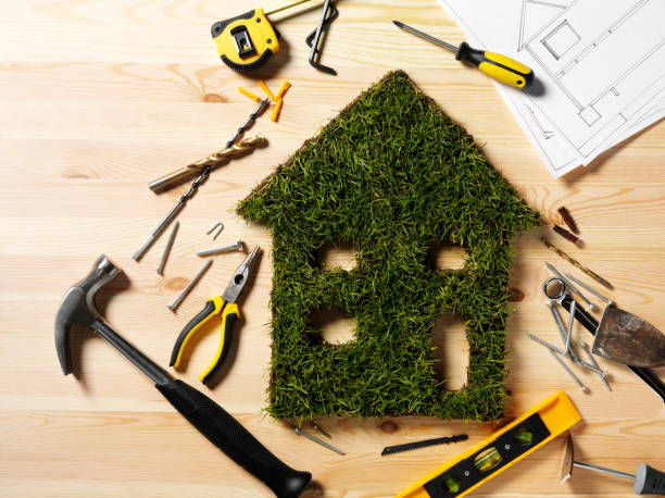 Construction of a Green Grass House Eco house cut out of grass with construction tools on a wooden background. work tool nail wood construction stock pictures, royalty-free photos & images