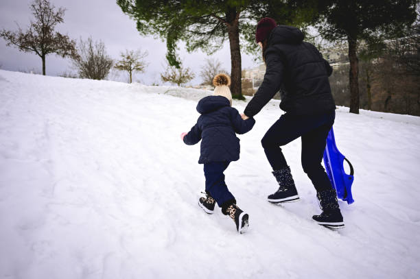 istock mother help daughter to pull up a sled on a hill. 1687178441