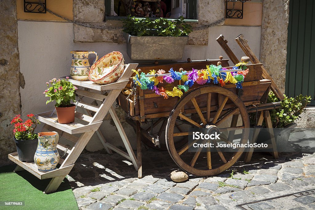 typical portuguese ceramics and small old wooden cart at the doors of a craft shop in Lisbon, Portugal Ceramics Stock Photo
