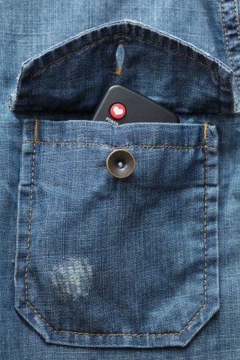 Remote control with a heart symbol on the red button in the denim shirt pocket. Close-up.