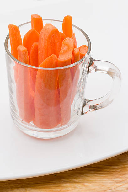 Clear glass cup full of sliced carrots on white plate stock photo