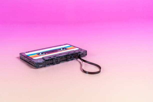 istock Transparent audio cassette with labels and output tape, on fuchsia background. 1687236352