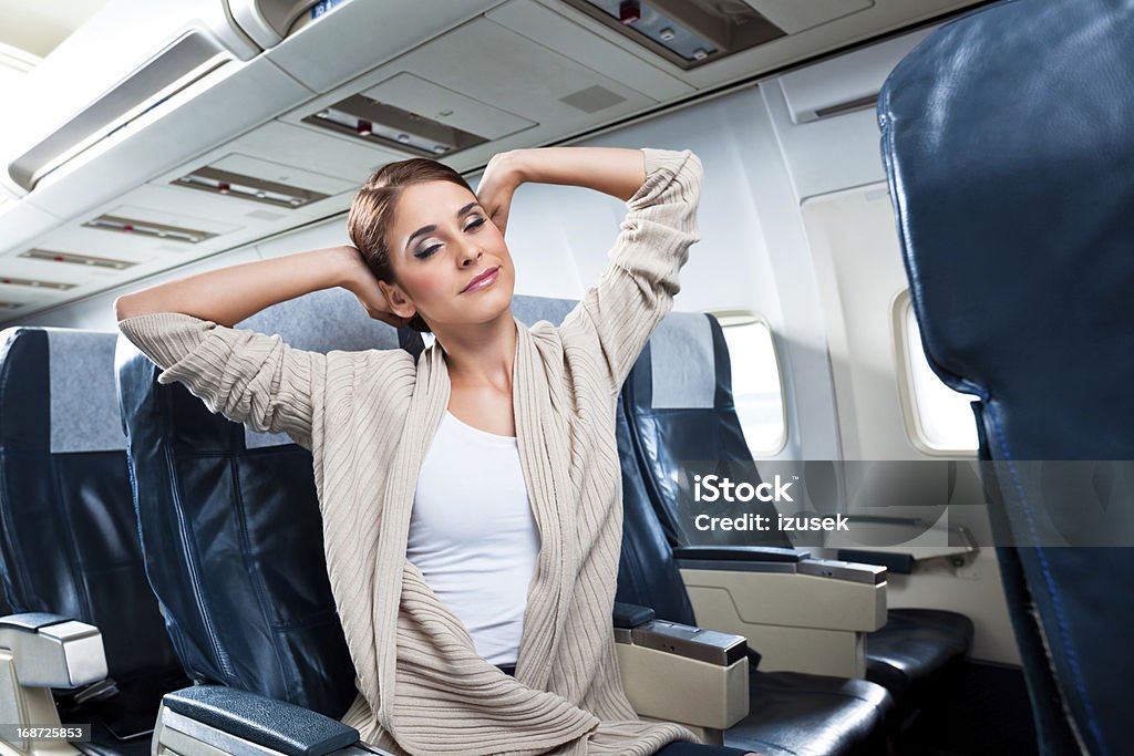 Woman on an airplane A young woman stretching during the flight. Stretching Stock Photo