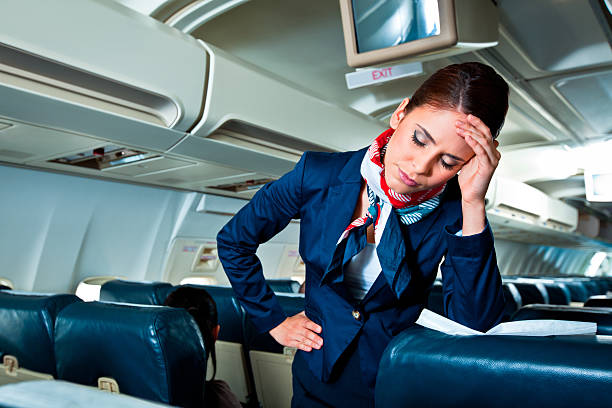 Tired air stewardess Young air stewardess suffering from headache on an airplane. crew stock pictures, royalty-free photos & images
