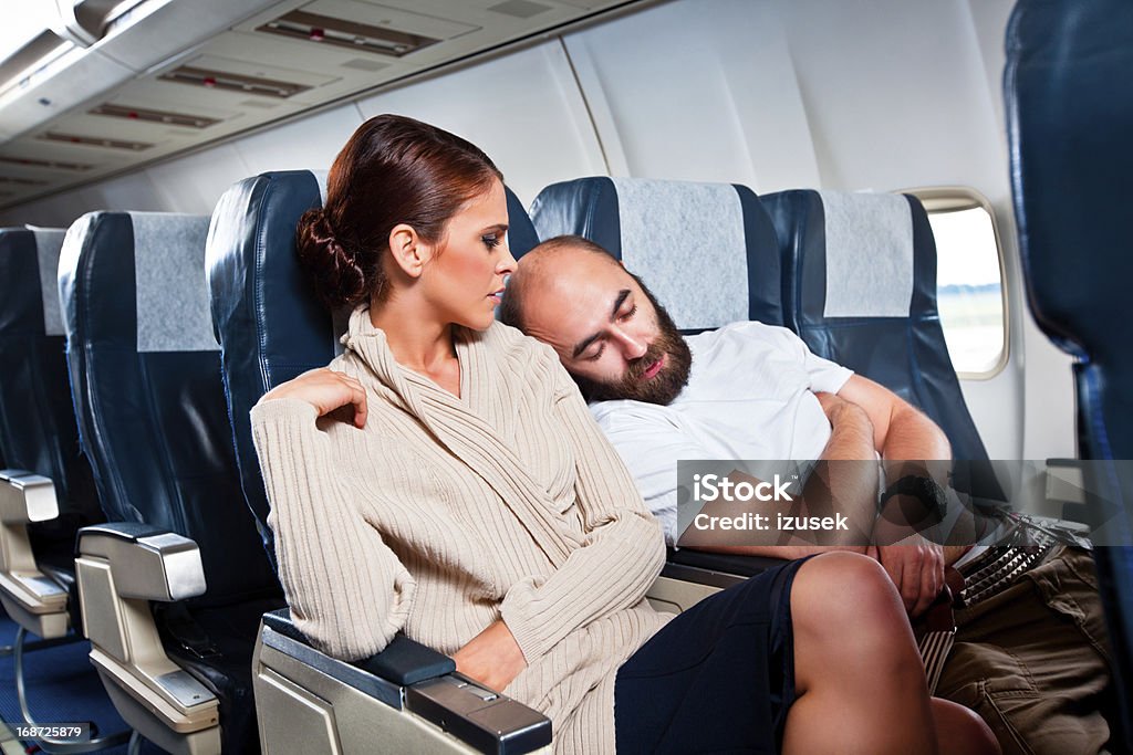 Rude passenger on the airplane Disgusted woman looking at the sleeping man sitting next to her, who rests his head on her shoulder. Airplane Stock Photo
