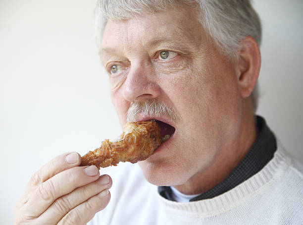 istock senior man eating fried chicken leg 168727587