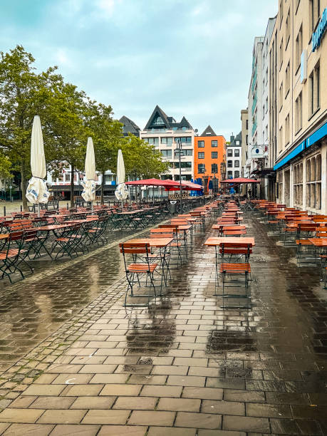 Cologne Germany Colorful City Square Cologne, Germany Colorful City Square on a Rainy Day. Empty outdoor cafe in the forefront of view. Modern and historical architecture surrounds the scene. rainy cafe stock pictures, royalty-free photos & images