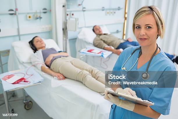 Nurse Next To Transfused Patients Writing On A Clipboard Stock Photo - Download Image Now