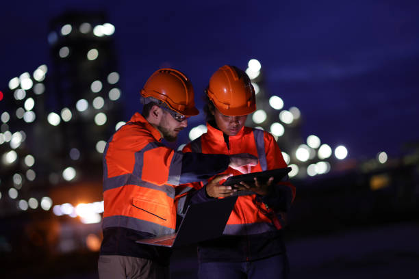 istock A couple of Electrical engineers with red safety jackets and hard hats using tablets and laptops working at a front factory on night shift. 1687319425