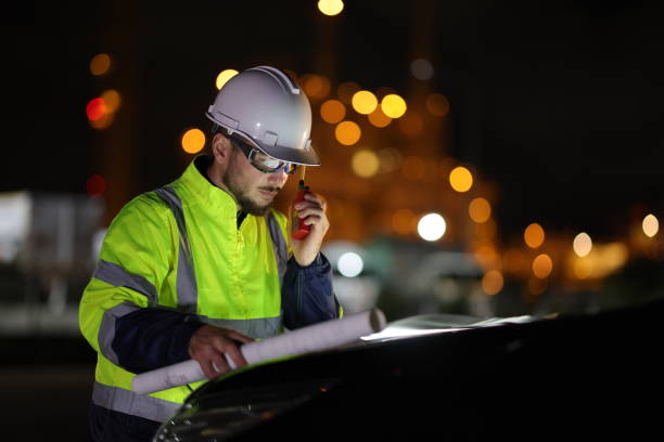 istock A portrait system engineer with a green safety jacket holds the drawing working on the hood of a car and using a walkie  talkie in a front factory on night shift 1687319448