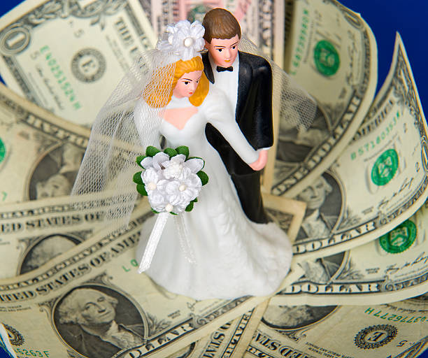 istock Bride and groom figurines surrounded by one dollar bills 168732971