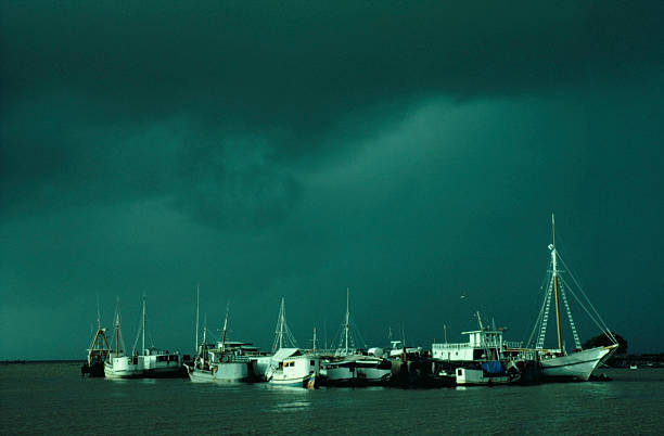 Sunburst on boats in harbor Dark ominous storm clouds over boats in a small harbour lit up by a sunburst in Cayenne, French Guiana guyana photos stock pictures, royalty-free photos & images