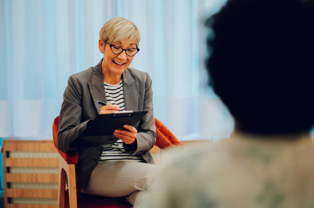 psychoterapeuta siedzi w gabinecie z klientem i spisuje notatki. - customer therapy asking doctor zdjęcia i obrazy z banku zdjęć