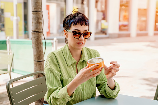 woman having coffee at the street cafe outside, talking on the phone and having fun time. lifestyle concept