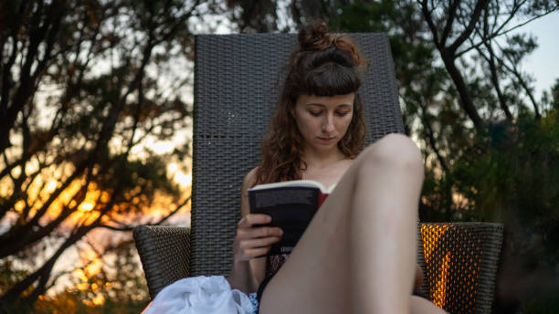 istock Young woman reading a book at the seaside 1687422054