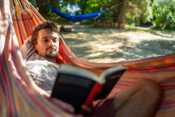 istock Young caucasian man reading a book in a hammock 1687422057