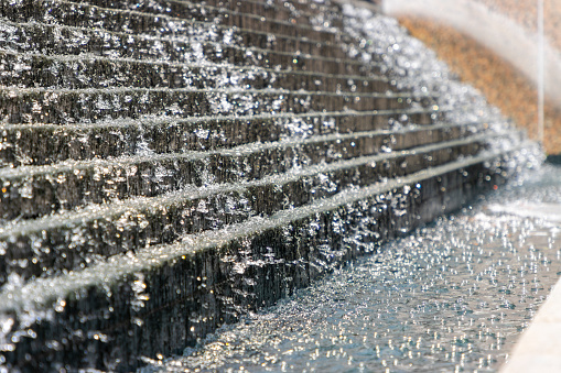 Sprinkling water of a fountain with detailed water drops glinstering in bright sunshine