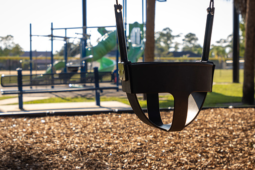 A swing seat for a toddler or baby in a public playground.