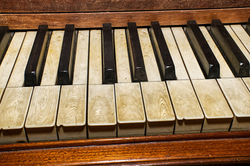 real elephant ivory piano keys on old wooden grand piano black and white keys with dirt, sweat and finger oils ground in detailed late 1800s instrument, worn, broken, damaged and well played top view