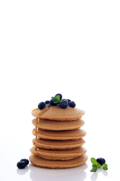 Stack of Delicious Pancakes with Fresh Blueberries, Mint Leafe,  and Maple Syrup Isolated on White Background