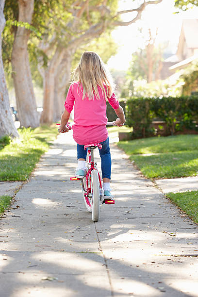 Girl Riding Bike Away From Camera Along Path