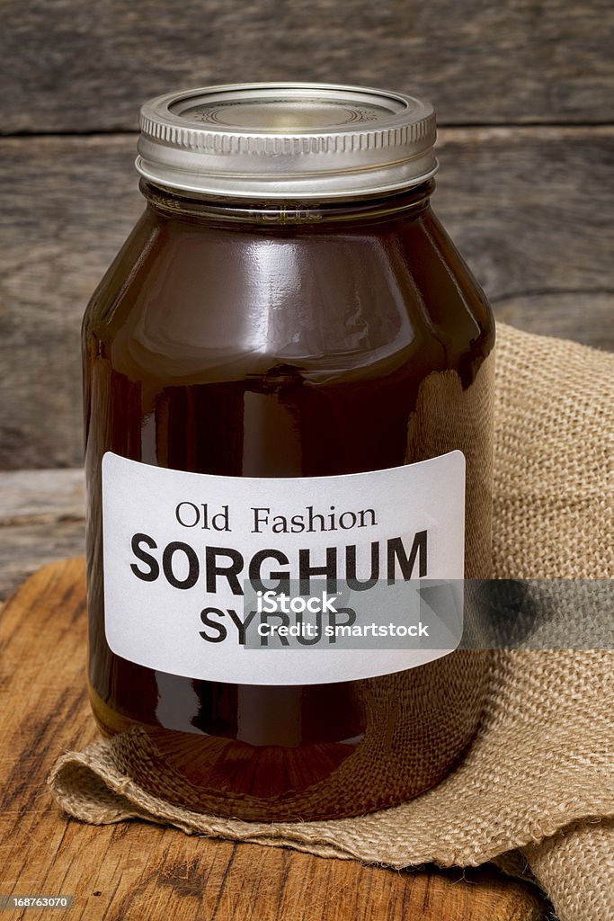 Artisanally Made Sorghum Syrup A quart jar of artisanally made sorghum syrup on a rustic background. Sorghum syrup, a sweetener made in the southeast USA for generations, is made from sorghum cane.  Sorghum Stock Photo