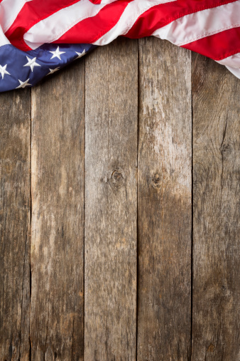 An American Flag Laying on an aged, weathered rustic wooden Background. 
