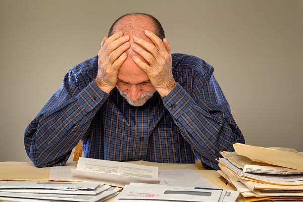 Deprimido Senior adulto homem com uma pilha de jornais e Envelopes - foto de acervo