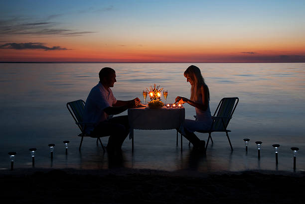 young couple share a romantic dinner with candles on beach