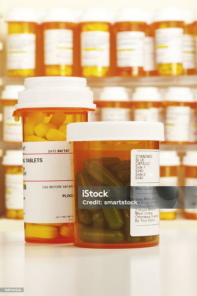 Zwei Tablette Flaschen mit Reihen von Medizin im Hintergrund - Lizenzfrei Medikamenten-Kapsel Stock-Foto