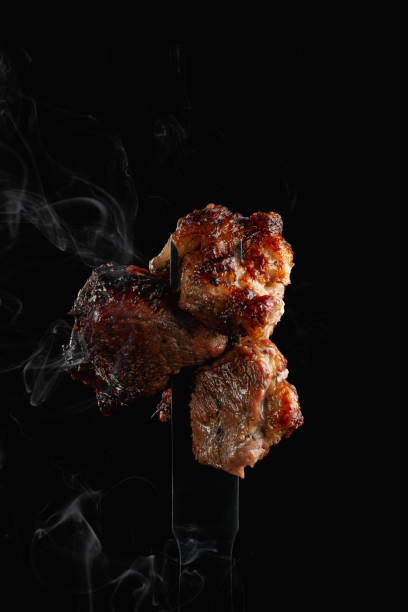 istock Grilled beef striploin on fork with smoke on dark background, close up. Classic Texas barbecue. Well Done BBQ 1687656232