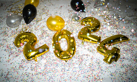 Greeting card concept for 2024 New Year, with gold foil numbers and scattered confetti