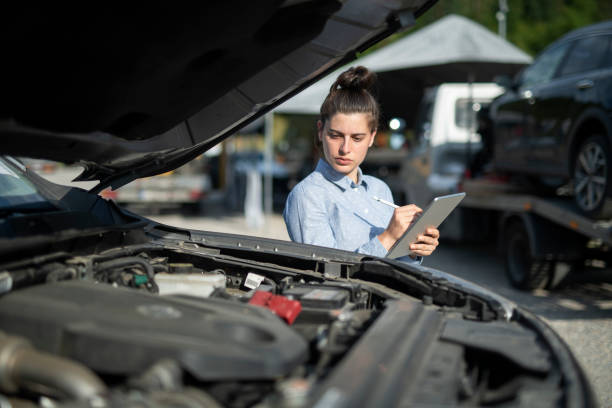 Insurance adjuster inspecting damage to vehicle. Female insurance adjuster inspecting gamage to vehicle using digital tablet. broken digital tablet note pad cracked stock pictures, royalty-free photos & images